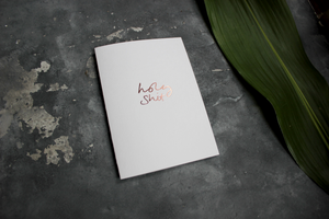 the words holy shit are handfoiled in rose gold foil on a luxury white paper