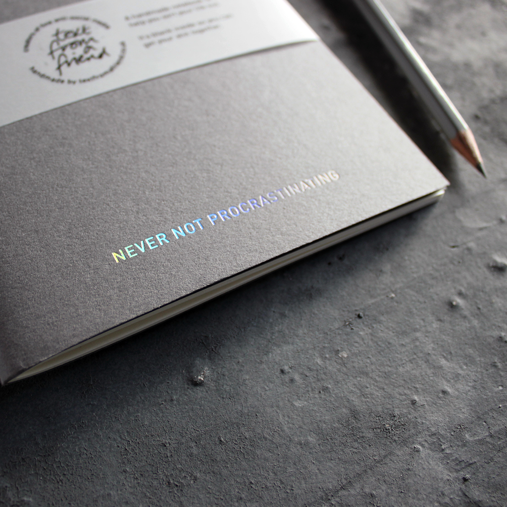 a grey handmade luxury notebook that's hand foiled with the message Never Not Procrastinating