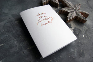 luxury white christmas card with the phrase Deck The Fucking Halls hand foiled in rose gold on the front