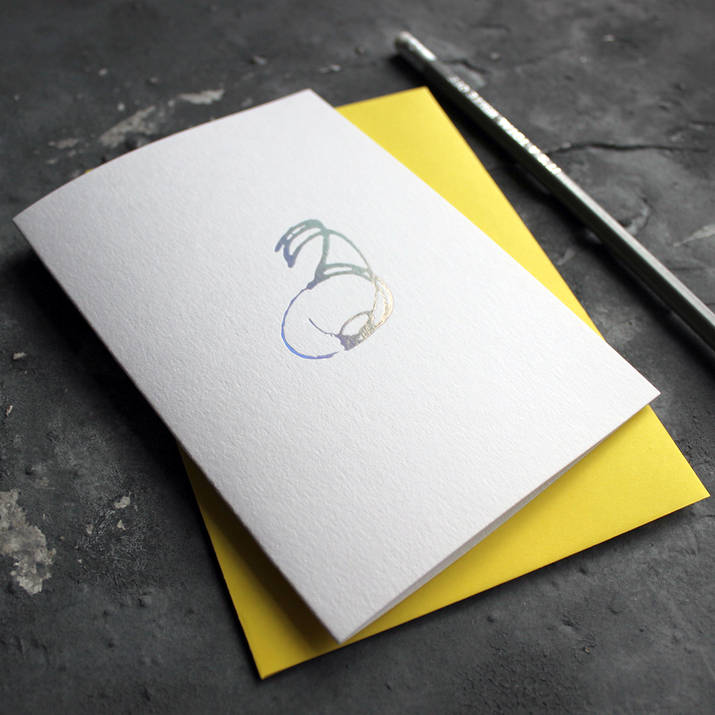 A third birthday card with a hand drawn number three hand pressed in holographic foil on the front and a yellow envelope