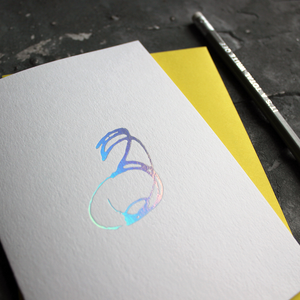 A third birthday card with a hand drawn number three hand pressed in holographic foil on the front