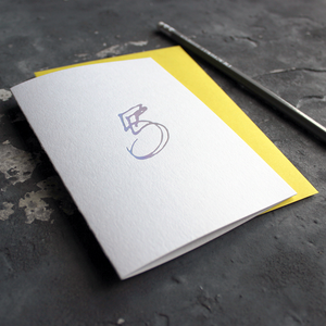 A fifth birthday card with a hand drawn number five hand pressed in holographic foil on the front and a yellow envelope