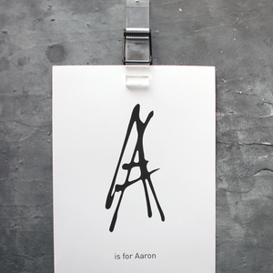 This personalised children's initial print is a unique hand drawn typography design in black on white paper.