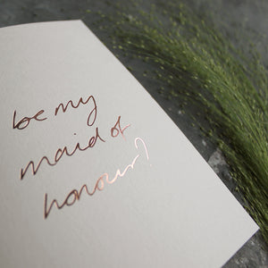 this hand foiled card asks 'be my maid of honour?' on the front in handwriting on blush coloured paper