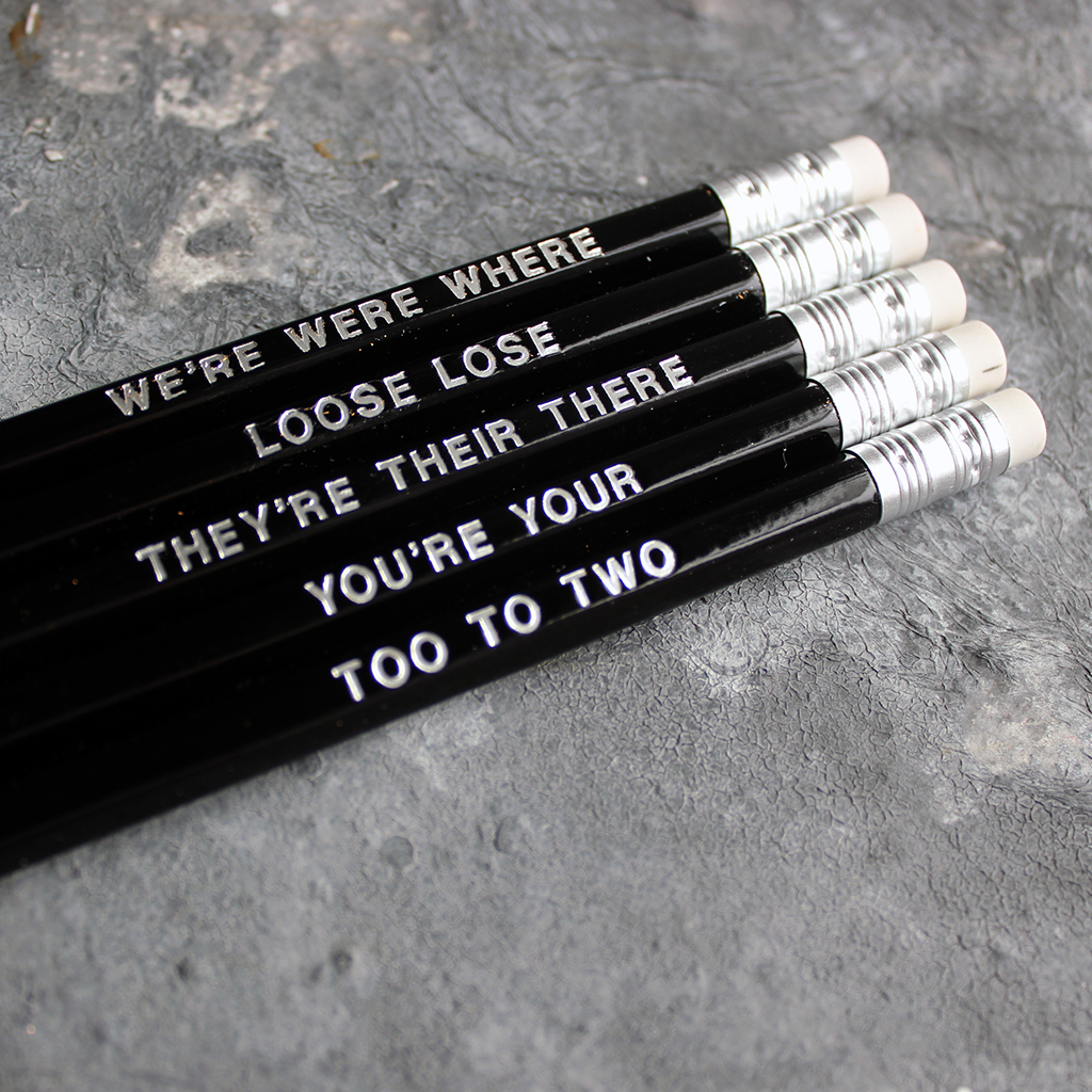 Black HB pencils printed with silver foil phrases and packaged in a grey paper box. 