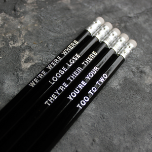 Black HB pencils printed with silver foil phrases and packaged in a grey paper box. 