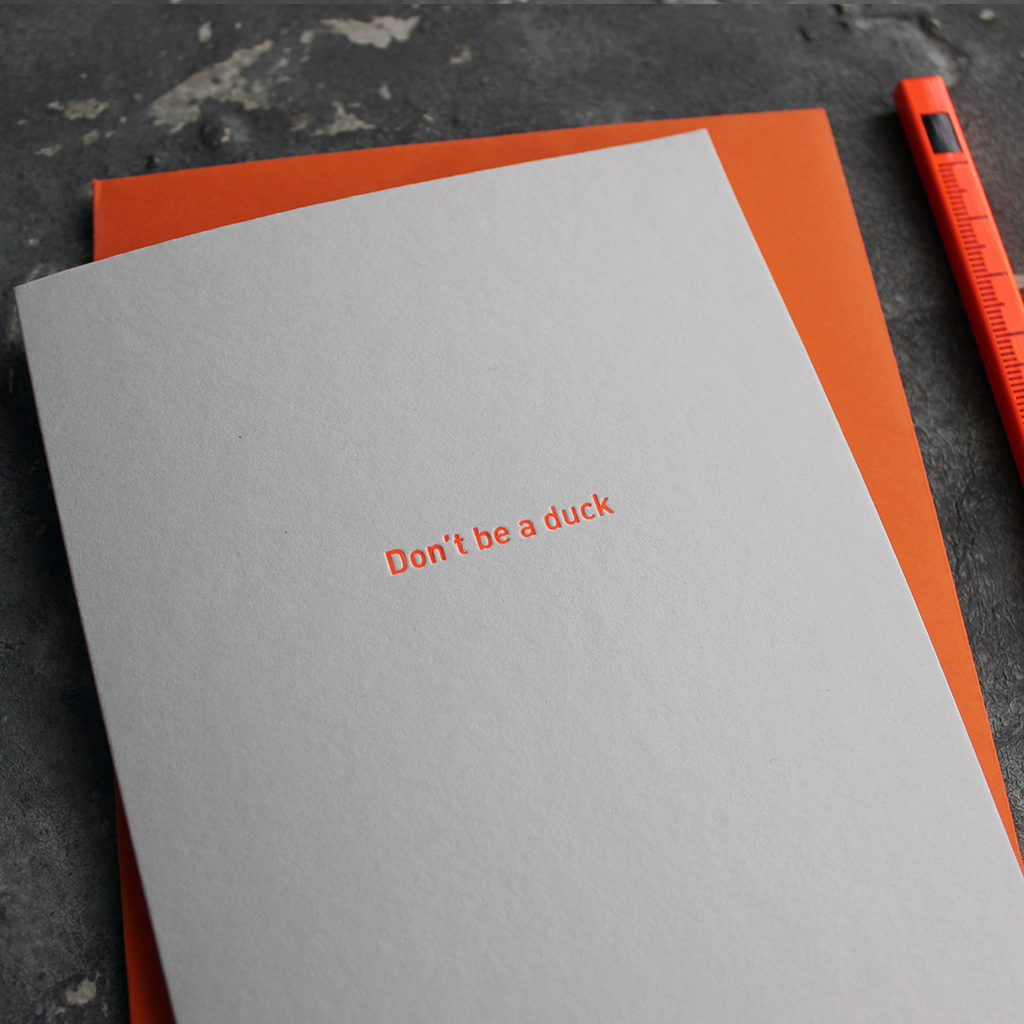 The front of the grey card says Don't Be A Duck and is stamped in neon orange foil