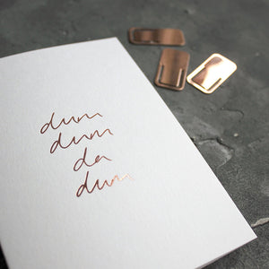 This rose gold hand foiled luxury white card says Dum Dum Da Dum on the front in handwriting from Text From A Friend
