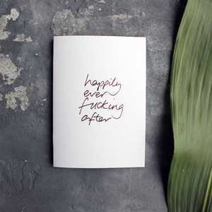 A rose gold hand foiled wedding card saying Happily Ever Fucking After 