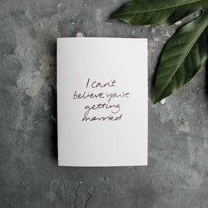 The front of the card has the phrase 'I can't believe you're getting married' handwritten and hand pressed in rose gold foil