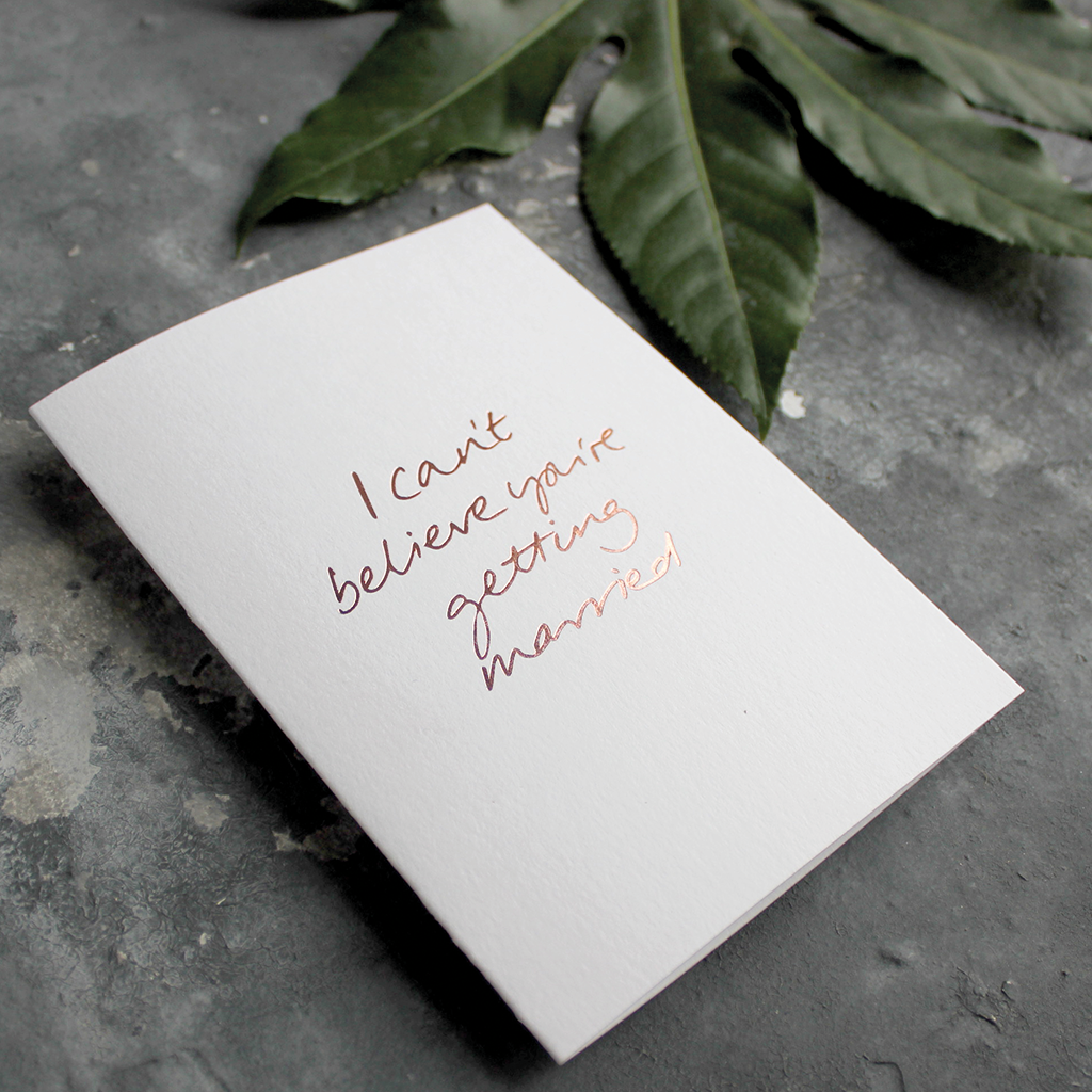 The front of the card has the phrase 'I can't believe you're getting married' handwritten and hand pressed in rose gold foil