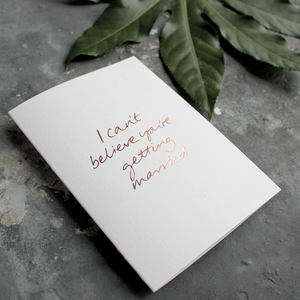 The front of the card has the phrase 'I can't believe you're getting married' handwritten and hand pressed in rose gold foil