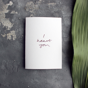 a luxury card that is handwritten with a rose gold foil message saying I Heart You