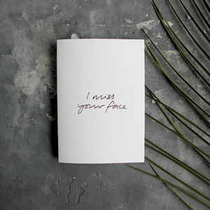 The front of this luxury card says I Miss Your Face, handwritten and hand foiled in rose gold foil