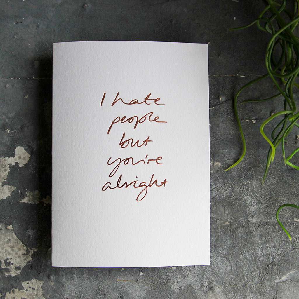 this hand foiled luxury white card says I Hate People But You're Alright on the front in rose gold foil