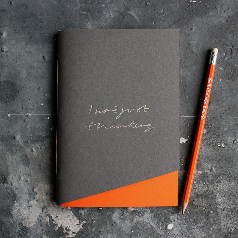 a grey and orange handmade luxury notebook that's hand foiled with the message I Was Just Thinking in holographic foil