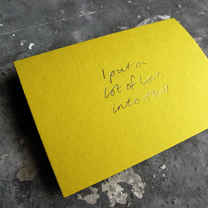 This cash card says I Put A Lot Of Love Into This and is handwritten and hand printed in pale lime foil on lime luxury paper on grey board