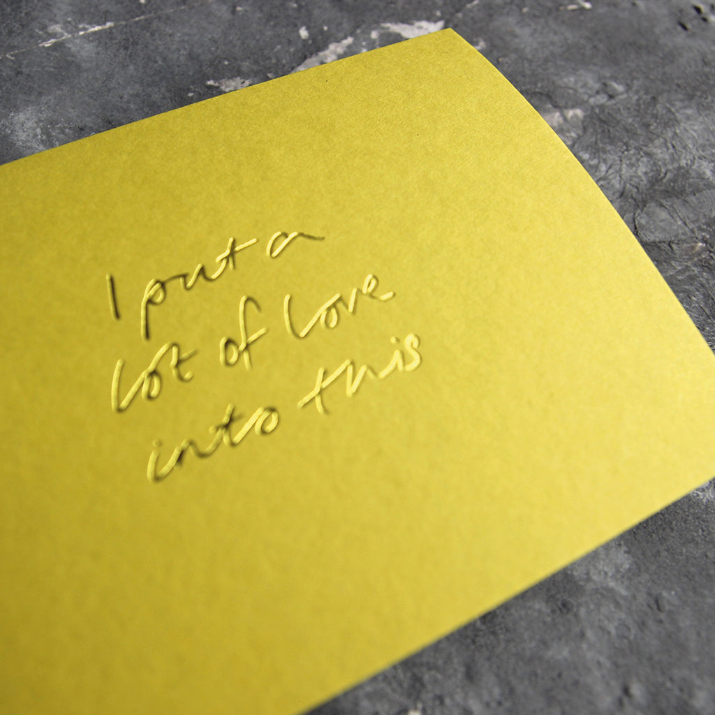 This cash card says I Put A Lot Of Love Into This and is handwritten and hand printed in pale lime foil on lime luxury paper on grey board