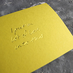 This cash card says I Put A Lot Of Love Into This and is handwritten and hand printed in pale lime foil on lime luxury paper on grey board