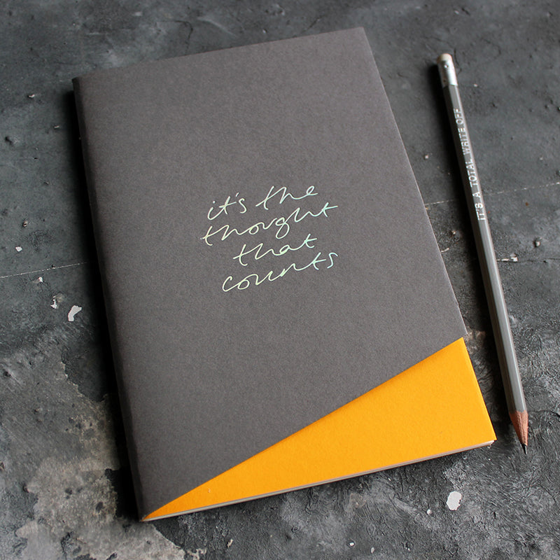 a grey and yellow coloured handmade luxury notebook that's hand foiled with the message It's The Thought That Counts in holographic foil
