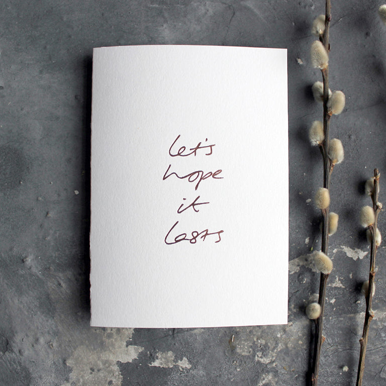 this hand foiled white luxury card say 'let's hope it lasts' on the front