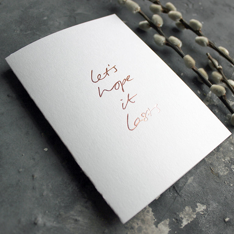 this hand foiled white luxury card say 'let's hope it lasts' on the front