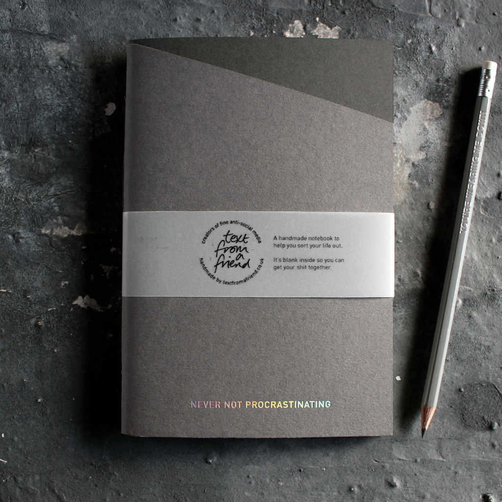 a grey handmade luxury notebook that's hand foiled with the message Never Not Procrastinating