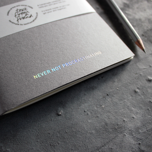 a grey handmade luxury notebook that's hand foiled with the message Never Not Procrastinating