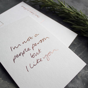 A luxury hand foiled postcard that says I'm Not A People Person But I Like You in rose gold foil