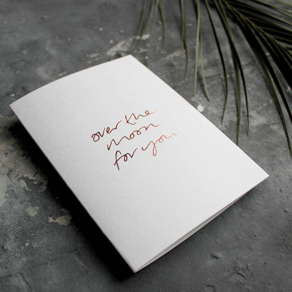 The front of this luxury card says Over The Moon For You and is handwritten and hand foiled in rose gold