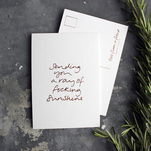 The Sending You A Ray Of Fucking Sunshine postcard is hand printed both sides in rose gold foil 