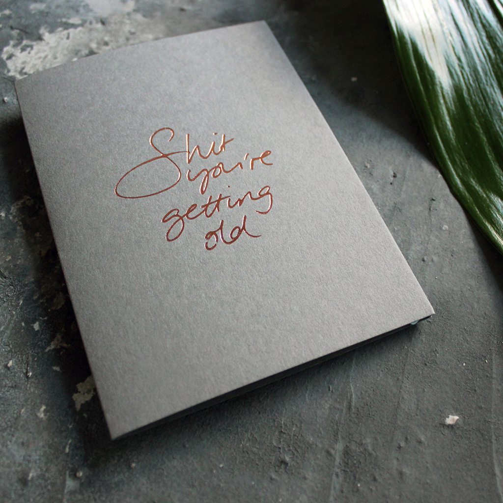 A luxury grey birthday card with the message 'Shit you're getting old' hand written and hand foiled in rose gold