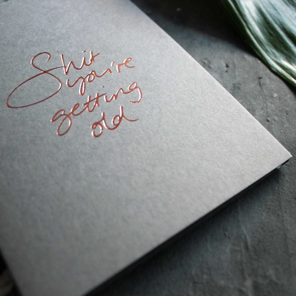A luxury grey birthday card with the message 'Shit you're getting old' hand written and hand foiled in rose gold
