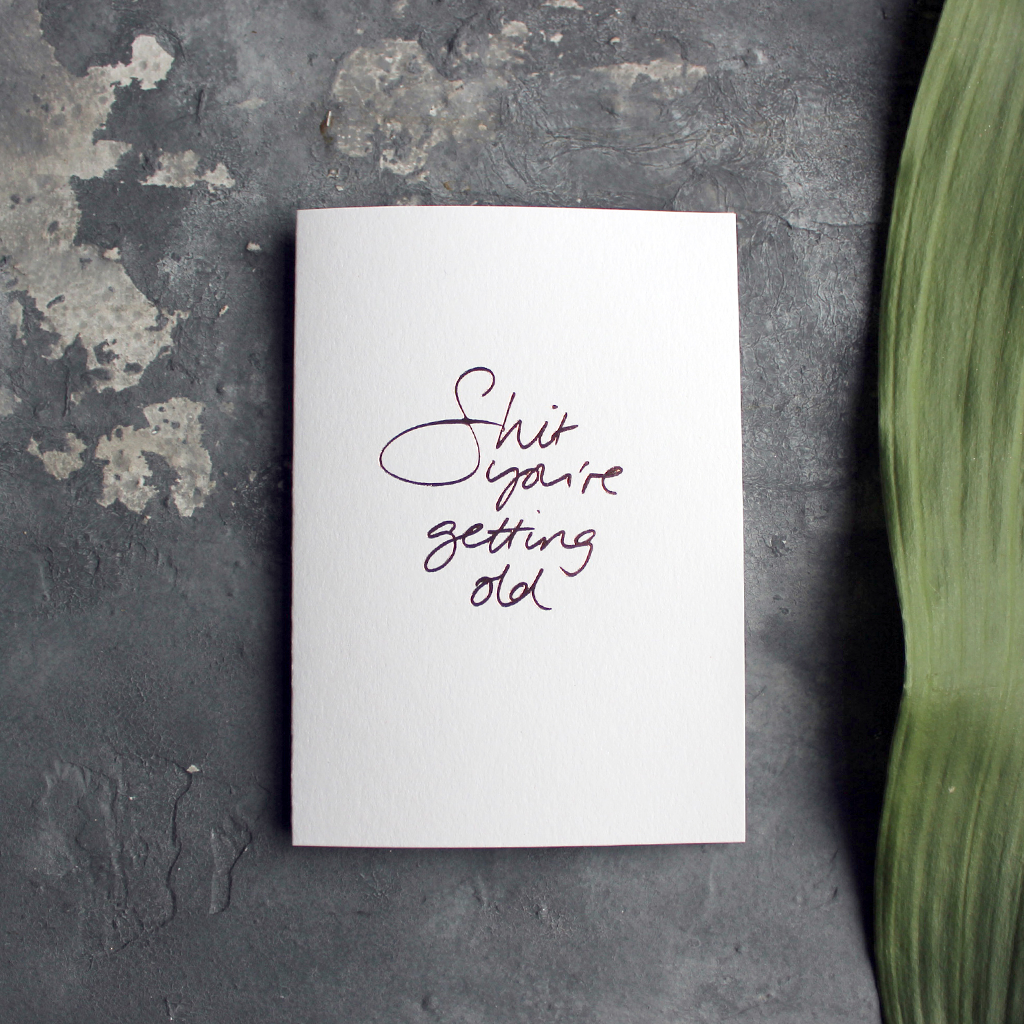 A birthday card with the message 'Shit you're getting old' hand written and hand foiled in rose gold