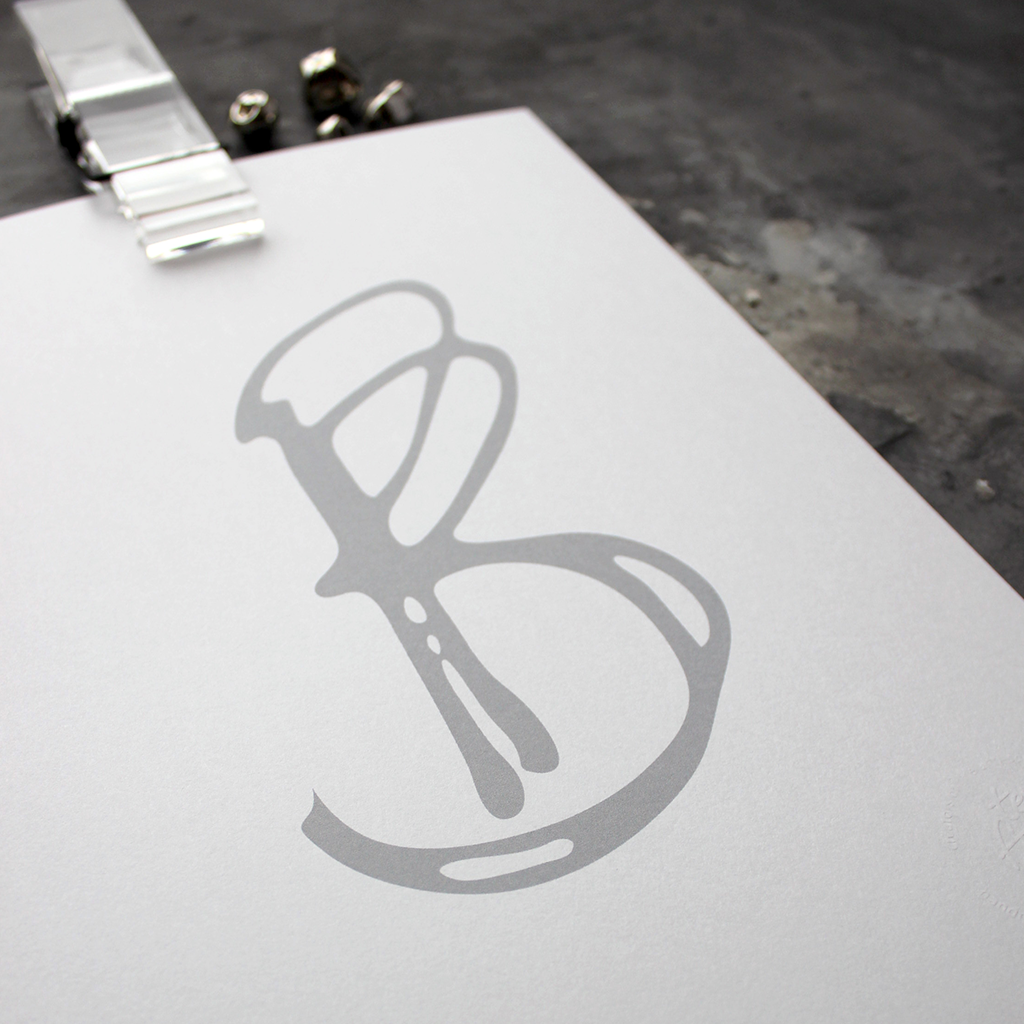 This initial print is a unique hand drawn typography design in grey on white paper.