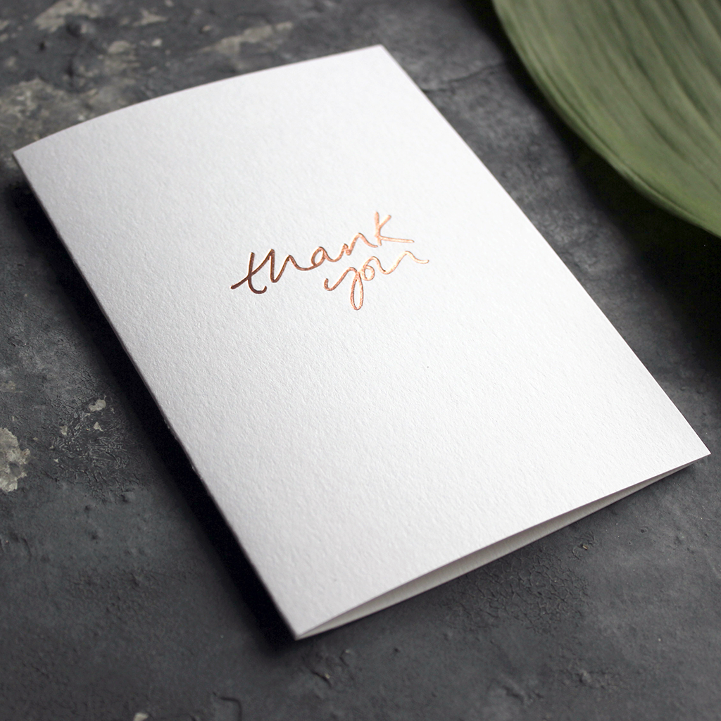 The front of the white luxury card says Thank You, handwritten and hand foiled in rose gold foil