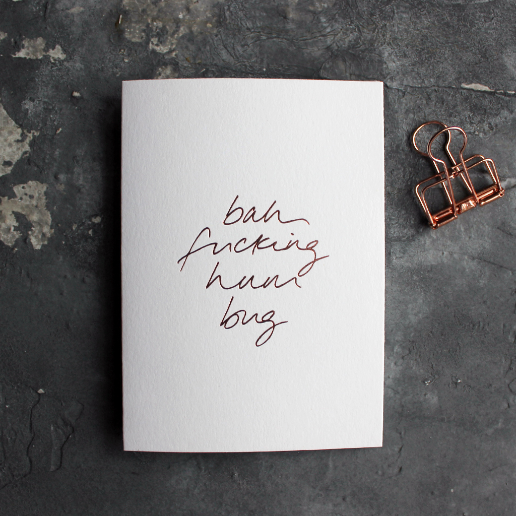 This white christmas card has 'Bah Fucking Hum Bug' handprinted in rose gold foil in handwriting on the front.