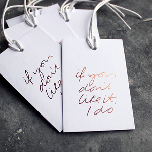 Luxury white gift tags with waxed cotton thread have "If You Don't Like It I Do' handprinted in handwritten rose gold foil.