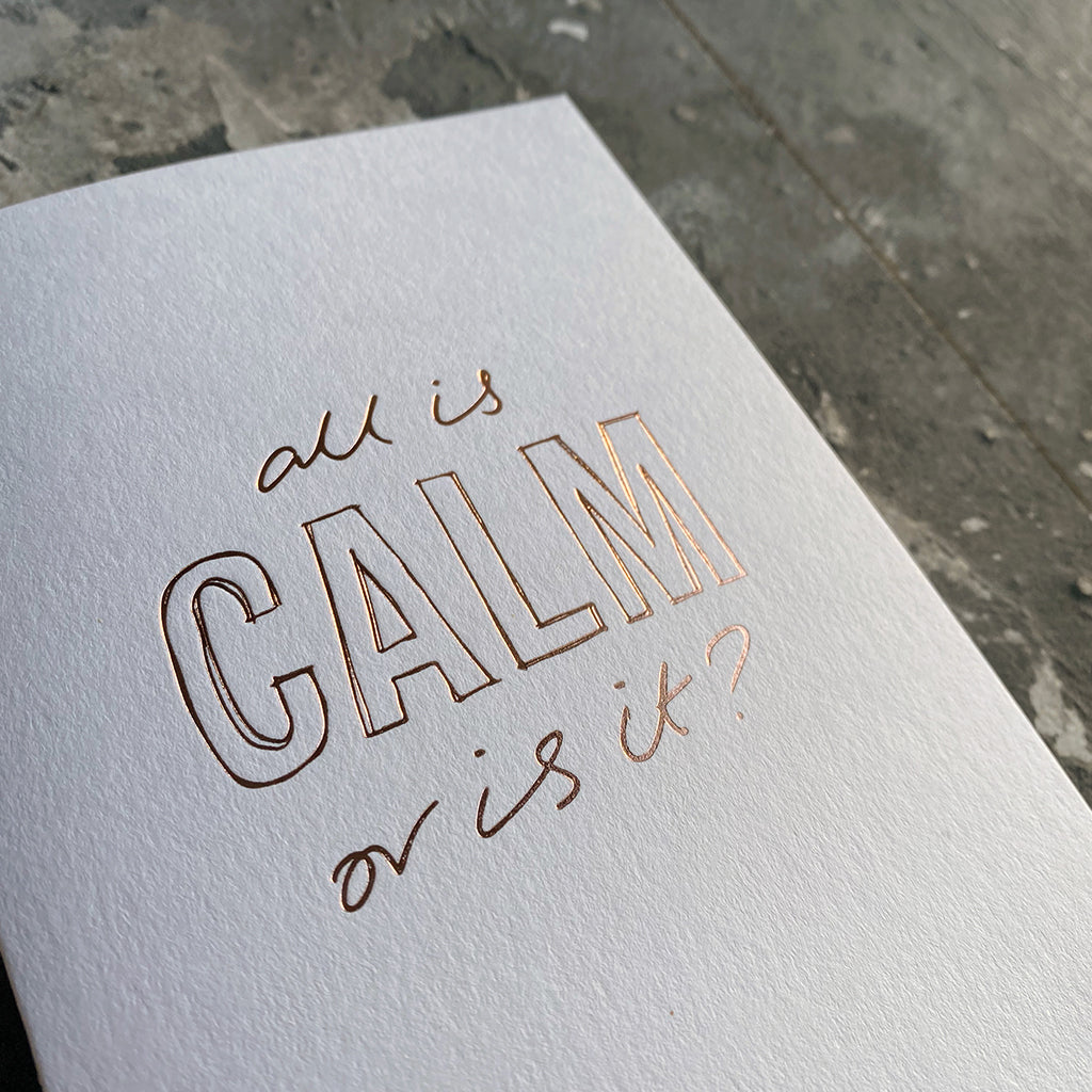 This luxury Christmas Card has a hand written rose gold foil block message saying All Is Calm Or Is It? on the front