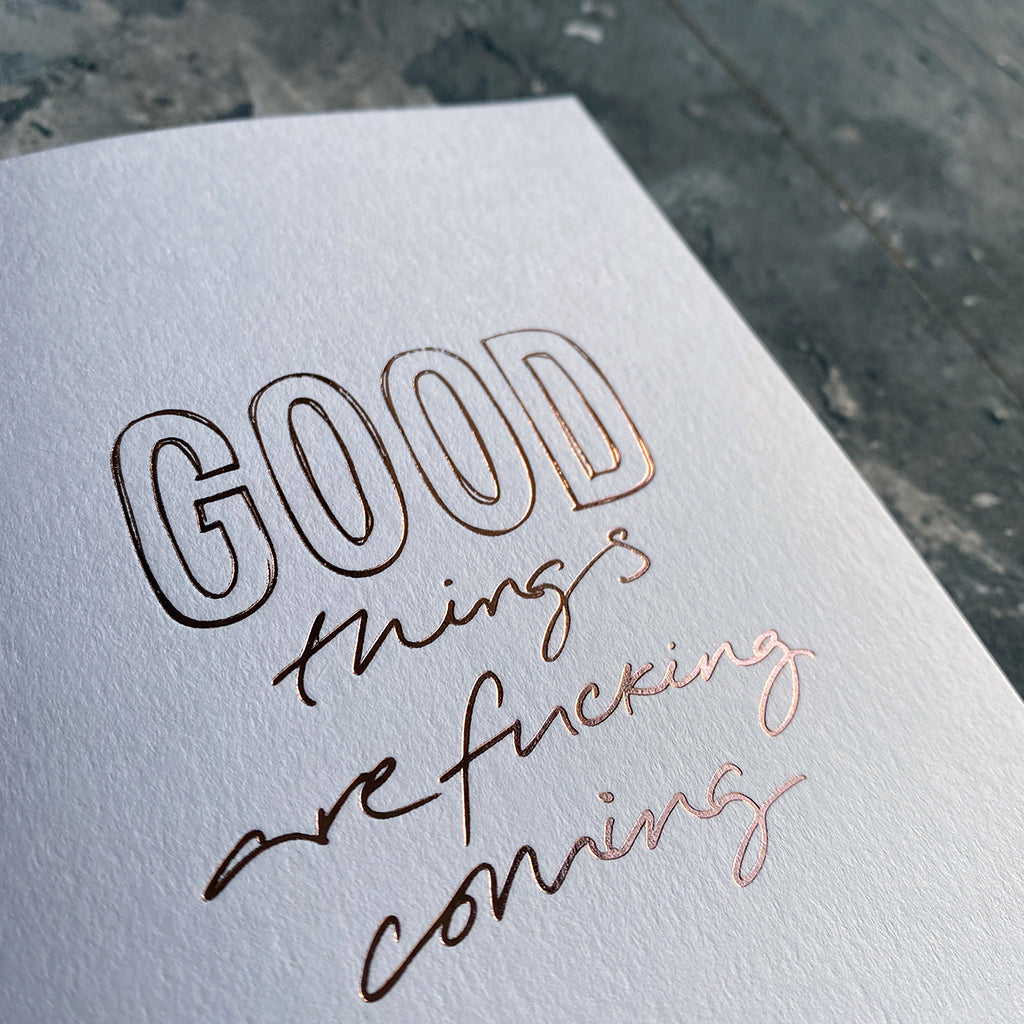 This luxury Christmas Card has a hand written rose gold foil block message saying Good Things Are Fucking Coming on the front