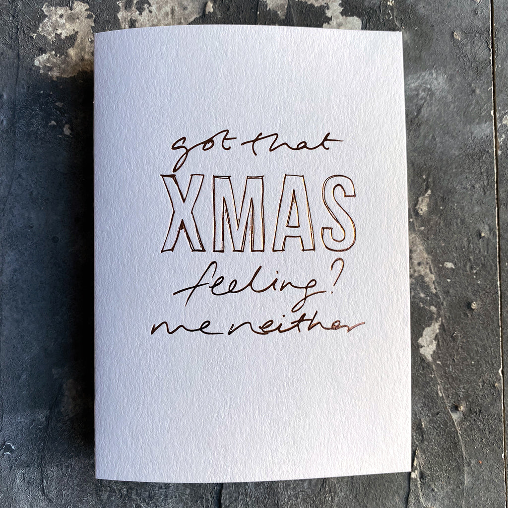 This luxury Christmas Card has a hand written rose gold foil block message saying Got That Xmas Feeling? Me Neither on the front