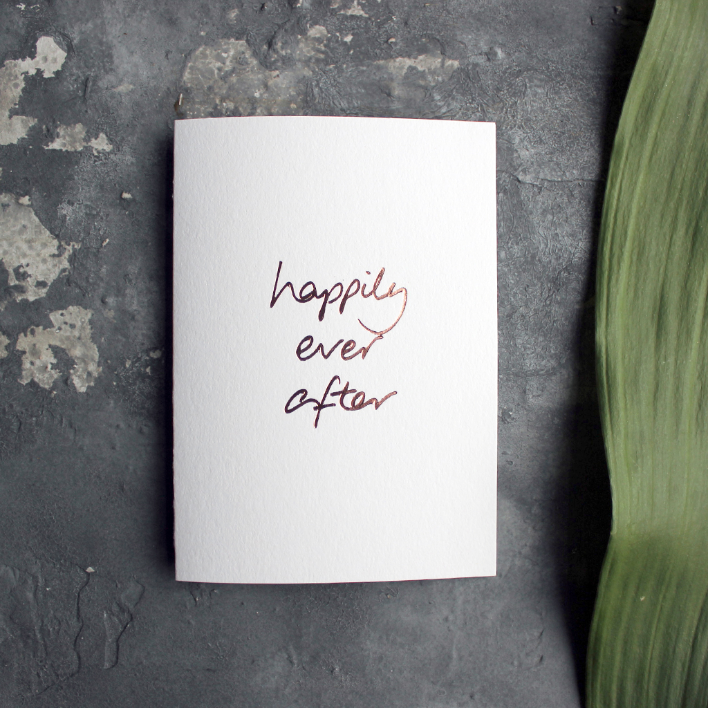 A rose gold hand foiled card saying Happily Ever After perfect a wedding