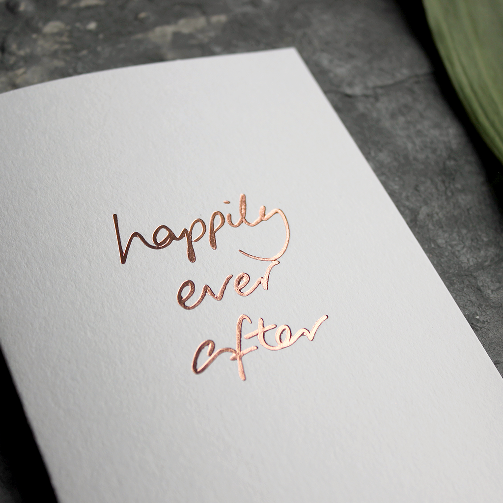 A rose gold hand foiled card saying Happily Ever After perfect a wedding
