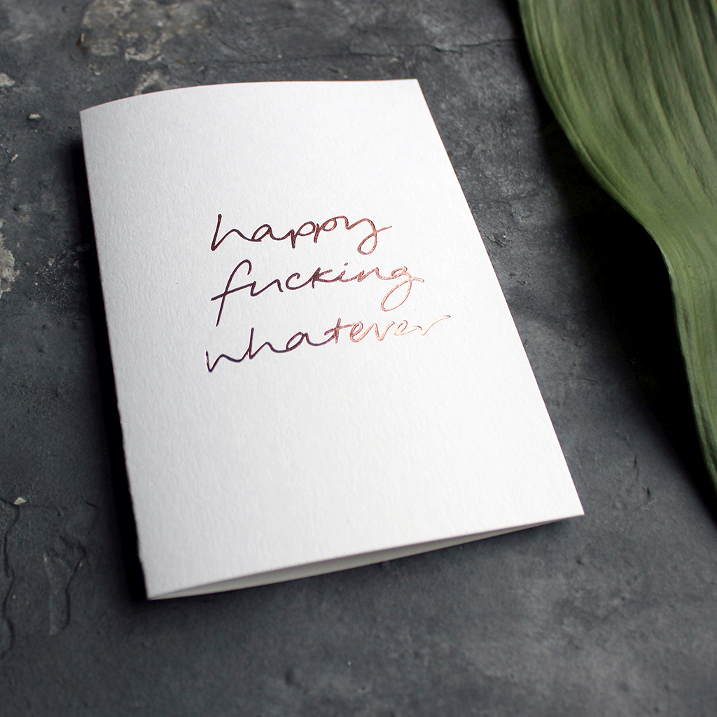 The handwritten rose gold foil message on the card says Happy Fucking Whatever