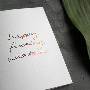 The handwritten rose gold foil message on the card says Happy Fucking Whatever