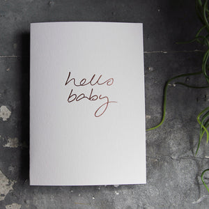 this hand foiled luxury white card says Hello Baby on the front in rose gold foil