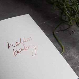 this hand foiled luxury white card says Hello Baby on the front in rose gold foil
