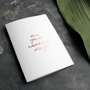 a luxury white wedding card that's handwritten with a rose gold foil message saying On Your Wedding Day