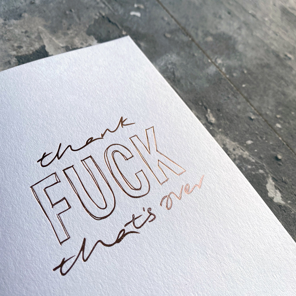 This luxury Christmas Card has a hand written rose gold foil block message saying Thank Fuck That's Over on the front