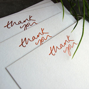 a group shot of luxury white notecards which are handfoiled in rose gold foil in handwriting and say thank you